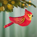 Decorative red and gold Cardinal ornament hanging on a Christmas tree.
