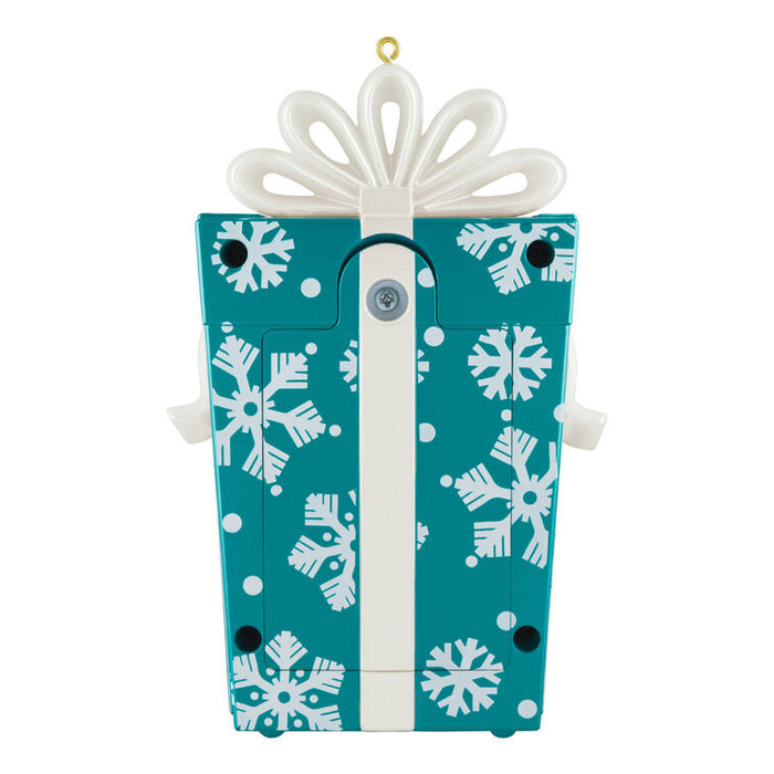 Decorative ornament shaped like a blue gift box with white snowflakes and a white bow on a white background.