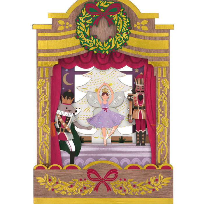 Decorative Nutcracker scene with fairy and soldiers in a wooden frame with wreath and ribbons.