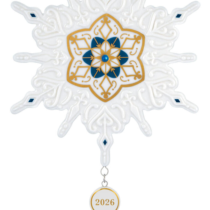 Decorative snowflake ornament with gold and blue design and '2026' tag on a white background