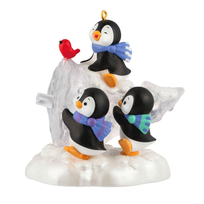 Ornament with penguins and a bird on a snowy base with an ice sculpted tree