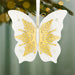 Decorative butterfly ornament with gold and white design on a blurred Christmas tree background
