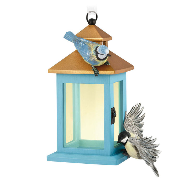 Blue birdhouse ornament with two birds on a white background