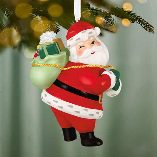 Santa Claus Christmas ornament hanging on a tree with a blurred festive background