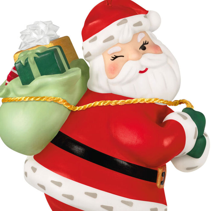 Santa Claus figurine holding a green sack with a gift on a white background