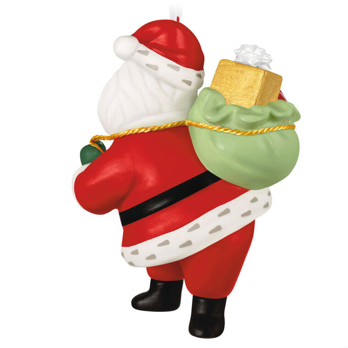 Decorative Santa Claus figure with a green sack and gift on a white background