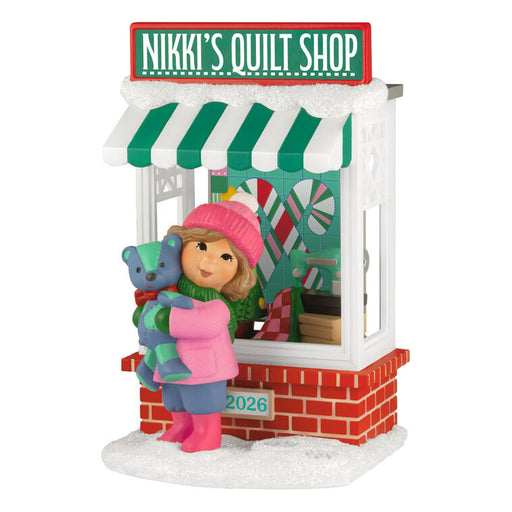Ornament of a girl holding a teddy bear in front of Nikki's Quilt Shop