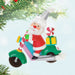 Christmas ornament of Santa Claus on a motorcycle with gifts, hanging against a light blue background.