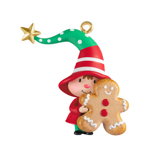 Christmas ornament of a gnome in a red hat holding a gingerbread man cookie on a white background