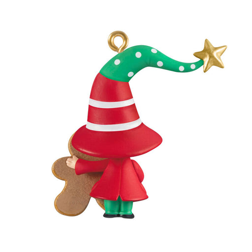 Christmas ornament of a gnome holding a gingerbread man with a red and green hat with a gold star on a white background