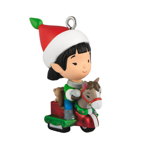 Christmas ornament of an elf with a elf hat riding a horse toy.