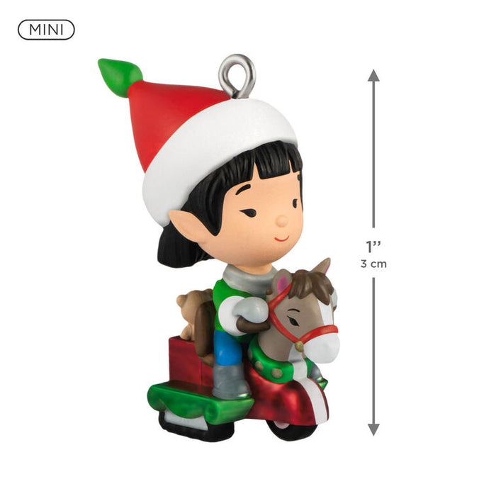 Miniature Christmas ornament of an elf with an elf hat and a small horse toy, with a measurement label on a white background.