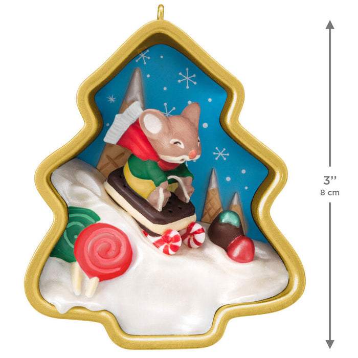 Decorative Christmas ornament with a mouse on a sledding on a hill accented with candy, and snowflakes.