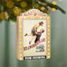 Decorative Christmas ornament with 'It's a Wonderful Life' movie poster design, hanging against a blurred green background.