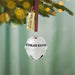 Silver bell ornament with 'The Polar Express' text, hanging on a Christmas tree branch.