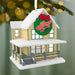 Christmas ornament of a house with a wreath displaying 'A Christmas Story' on a blurred green background.