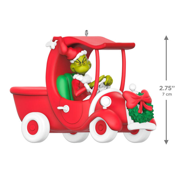 Decorative ornament of the Grinch in a red truck sleigh on a white background.