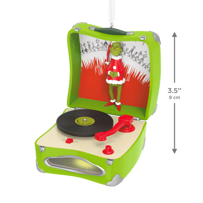 Decorative ornament resembling a record player with he Grinch in a Santa outfit inside, on a white background.