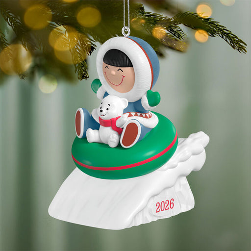 Christmas ornament featuring a child in a snowy scene with a polar bear, hanging on a tree.