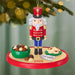 Christmas ornament of a nutcracker with cookies and nuts on a green background