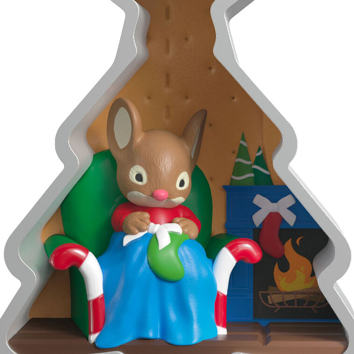 Mouse character in a cozy cabin with a fireplace, holding a gift.