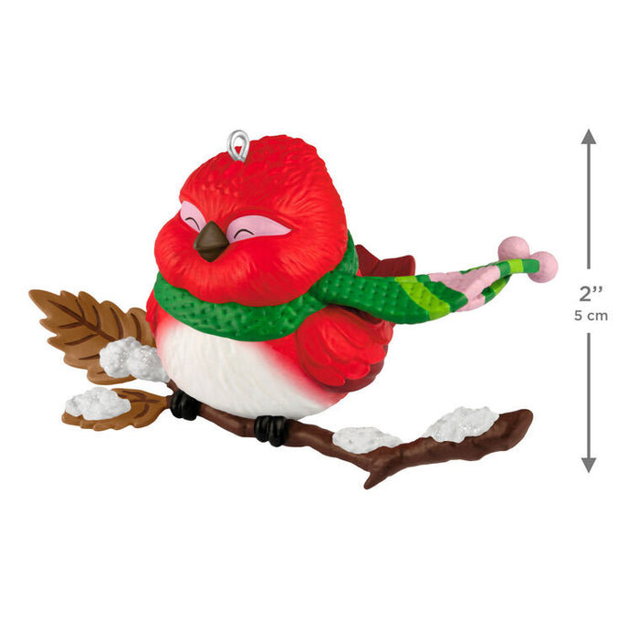 Red bird ornament with a green scarf on a branch, with size measurement indicated.