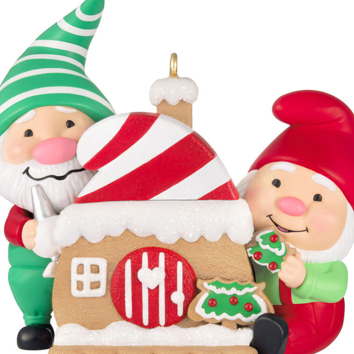 Decorative ornament with two elves and a gingerbread house on a white background