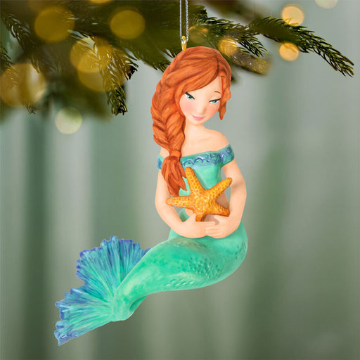 Mermaid ornament holding a starfish against a blurred green background