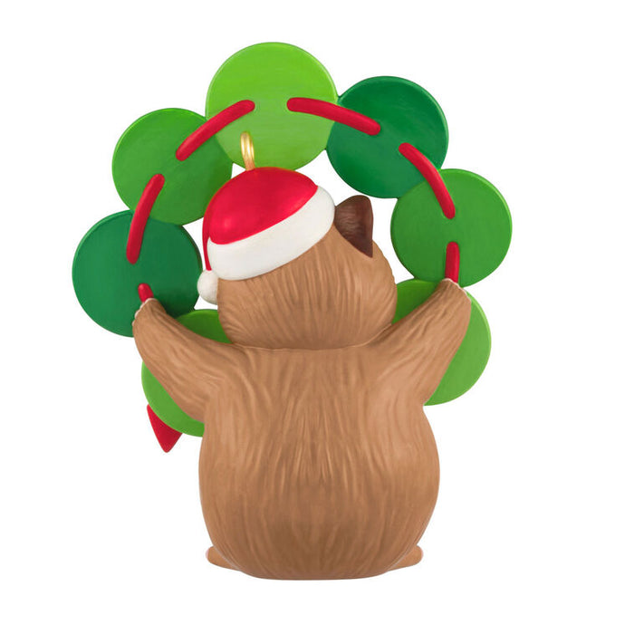 Hamster-shaped Christmas ornament with a Santa hat and green leaves on a white background