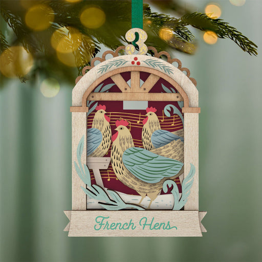 Decorative Christmas ornament with chickens and 'French Hens' text, hanging on a tree.