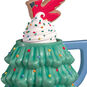 Green Christmas tree-shaped mug with a cookie on top against a white background