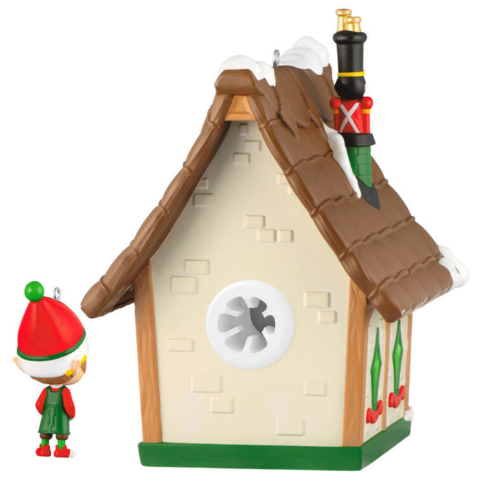 Decorative house with a small figurine wearing an elf hat on a white background