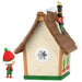 Decorative house with a small figurine wearing an elf hat on a white background