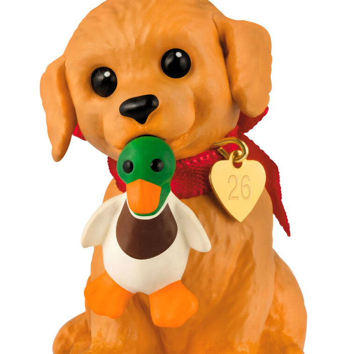 Dog figurine with a duck toy in its mouth and a heart-shaped tag on a white background