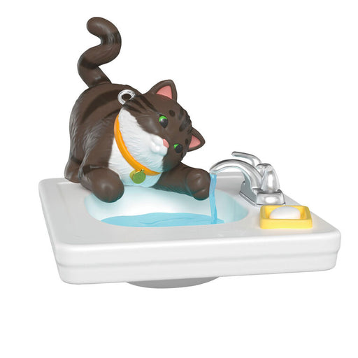 Cat figurine sitting on a sink with water flowing, on a white background