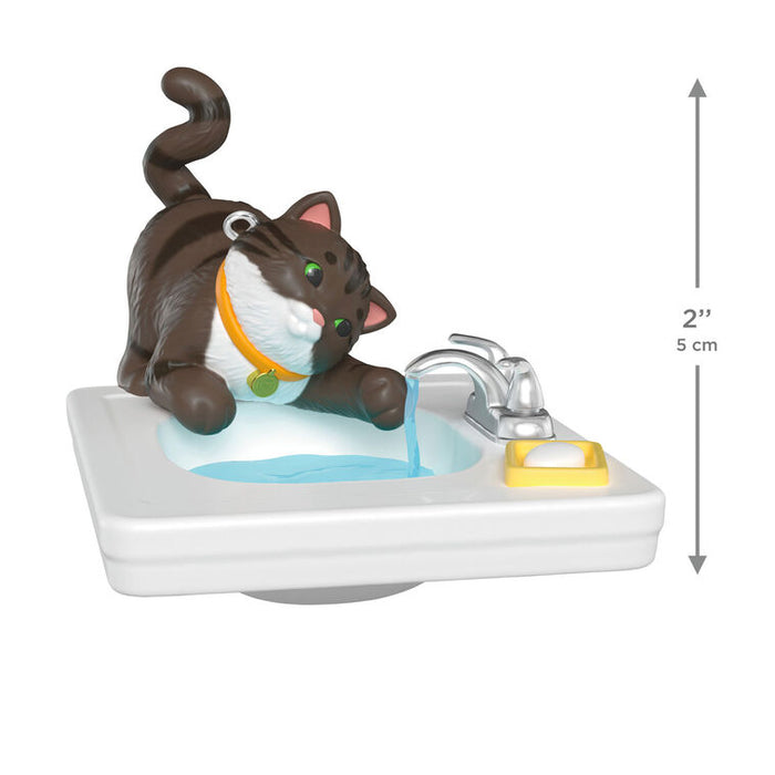 Cat figurine on a sink with water flowing, showing size measurement.