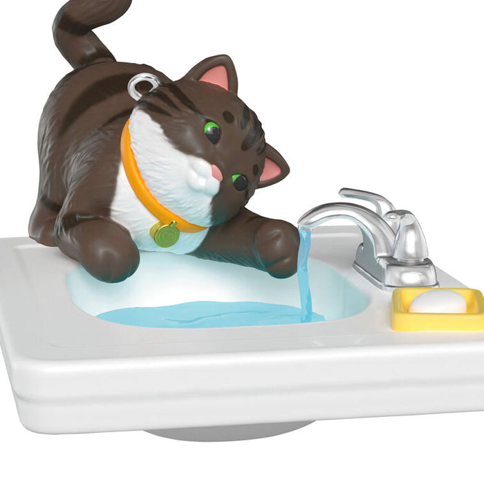 Toy cat figure interacting with a sink and faucet on a white background