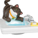 Toy cat figure interacting with a sink and faucet on a white background