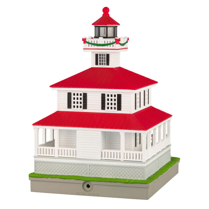 Model of a lighthouse with a red roof and white base on a white background