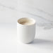 White candle in a ceramic holder on a marble surface