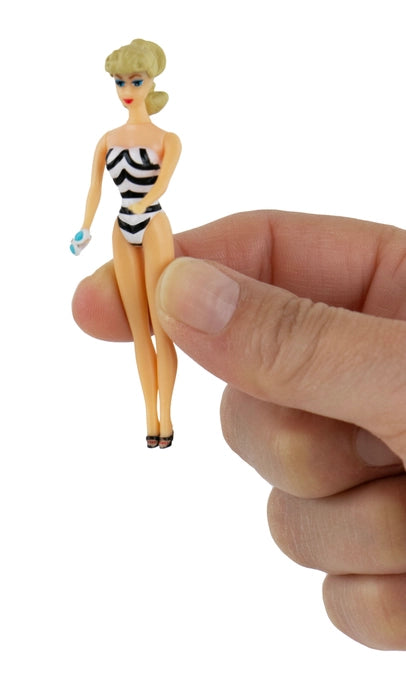 Small figurine of a woman in a striped swimsuit held between fingers against a white background