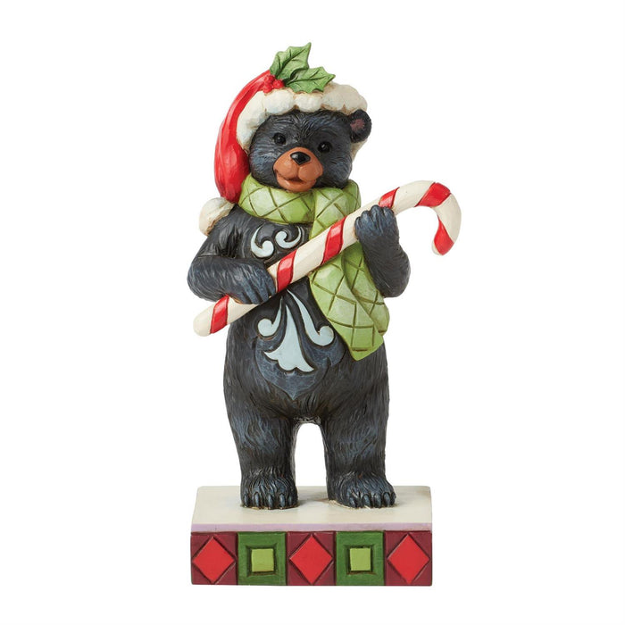 Christmas bear figurine holding a candy cane on a white background