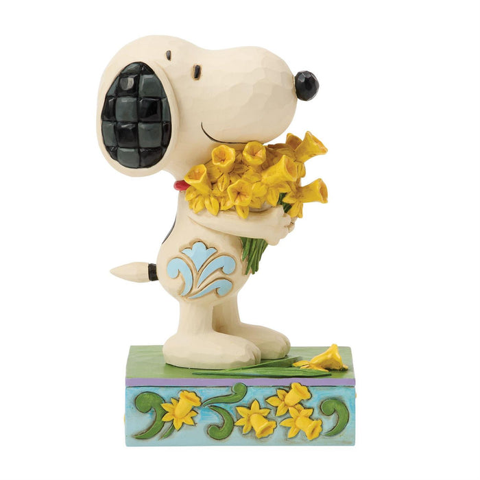 Snoopy figurine holding yellow flowers on a white background