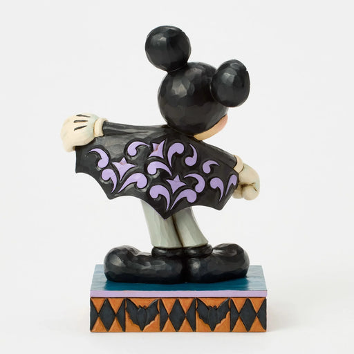 Mickey Mouse figurine in a Halloween costume with a black cape and purple accents on a white background.