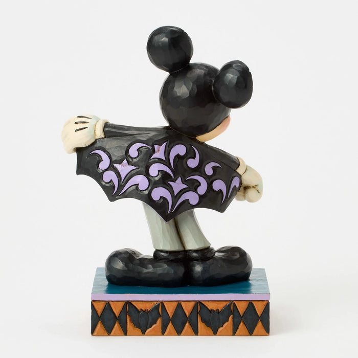 Mickey Mouse figurine in a Halloween costume with a black cape and purple accents on a white background.