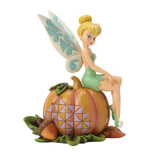 Disney fairy figurine sitting on a pumpkin with a white background