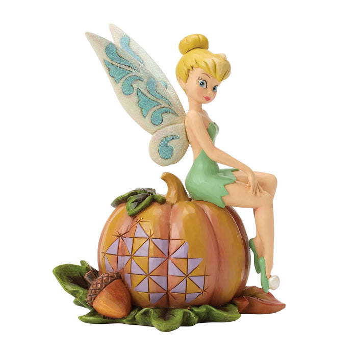 Disney fairy figurine sitting on a pumpkin with a white background