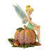 Disney fairy figurine sitting on a pumpkin with a white background