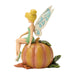 Fairy figurine sitting on a pumpkin with a white background