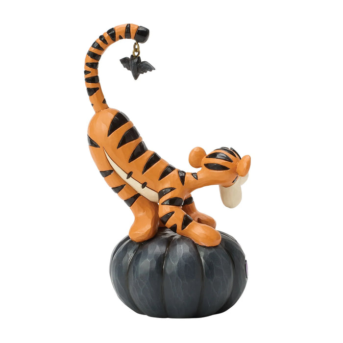 Tigger figurine on a pumpkin with a bat decoration on a white background